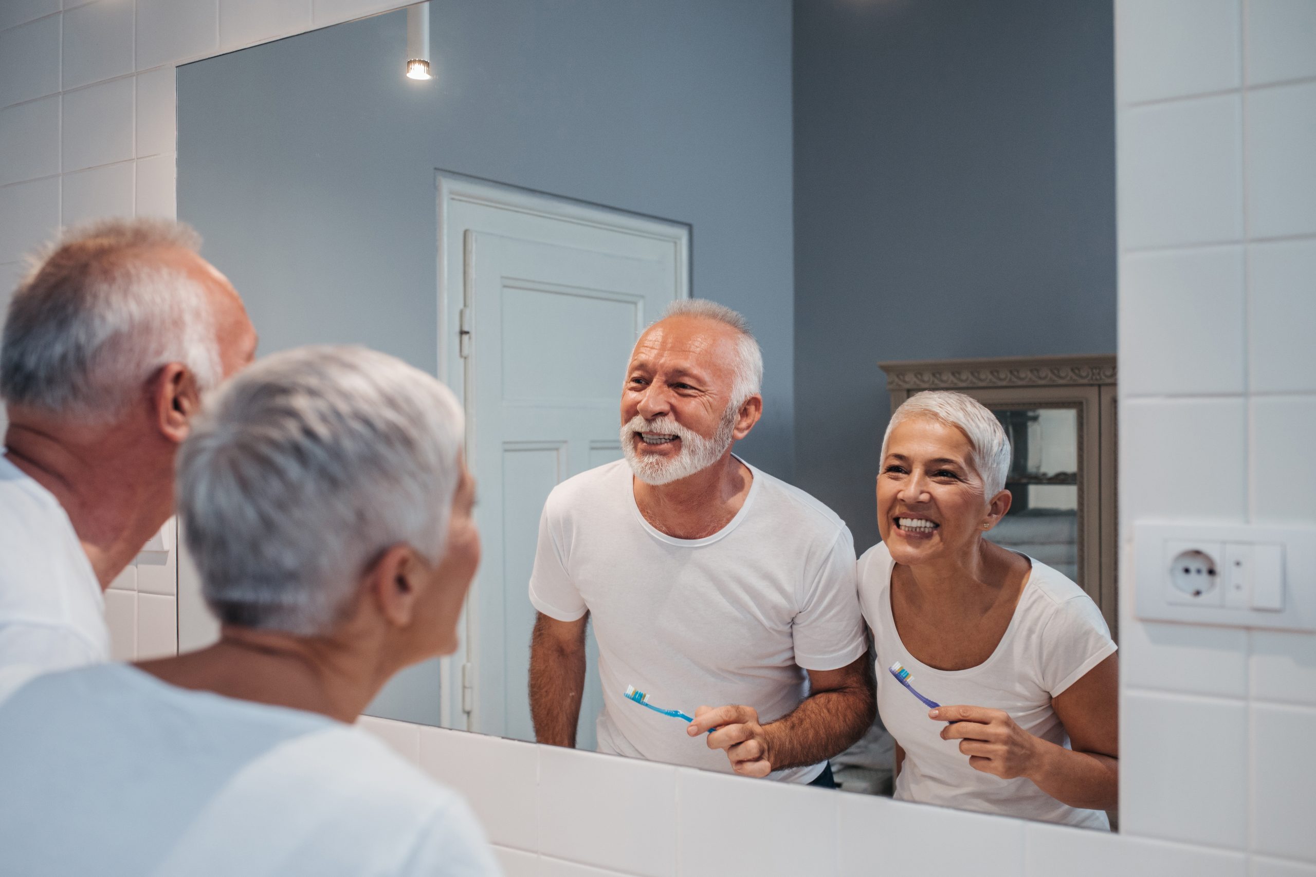 A senior couple comparing their white teeth after brushing up in the morning.