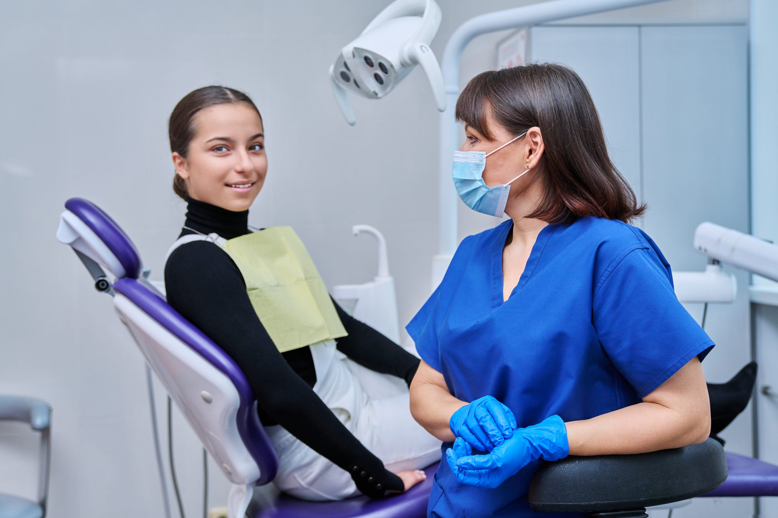 Female dentist with young teenage girl patient sitting in dental chair. Dentistry, hygiene, treatment, medicine, specialist, career, dental health care concept